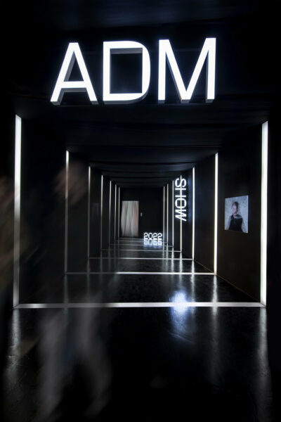 Inside view of the ADM Show—black hall with white signs and mesmerizing lighting.