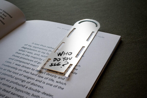 Close-up of a page from the Jekyll & Hyde publication paired with a branded bookmark asking "Who do you see?"