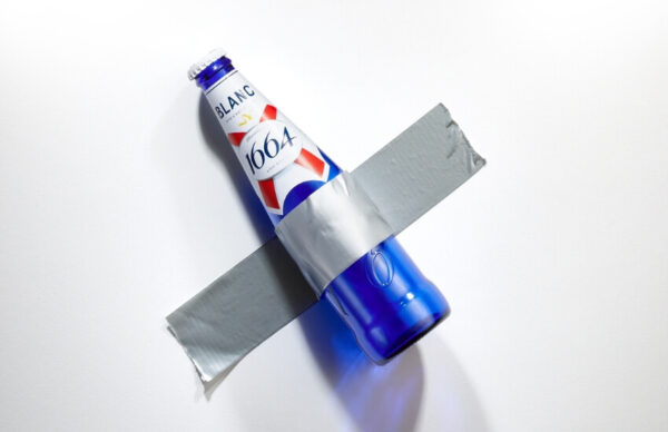 Kronenbourg Blanc bottle humorously taped to a gallery wall.