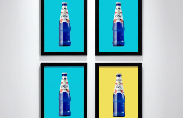 Four framed prints of the Kronenbourg Blanc bottle, three on a blue background and one on a yellow background.