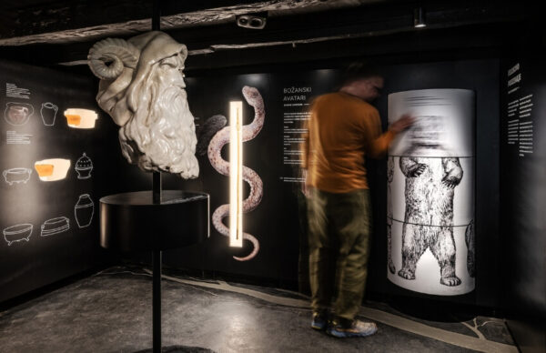A visitor viewing wall visuals and a central sculpture in the exhibition
