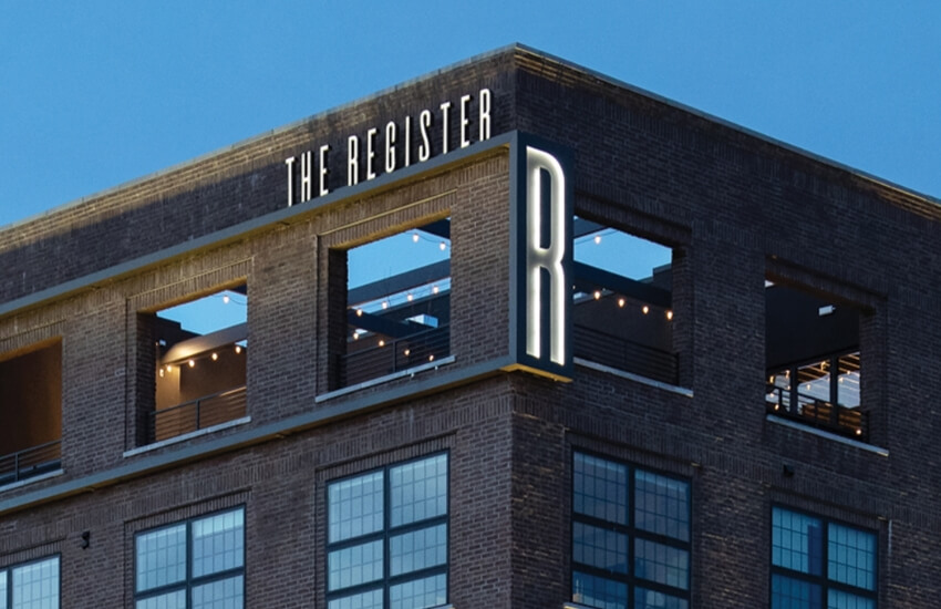 The Register logo mounted atop the Post District building against the sky